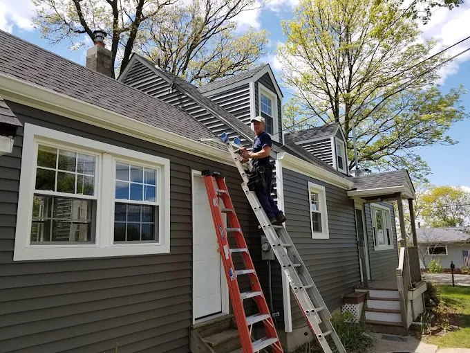 GLF Siding specialist repairing gutter and siding on ladder